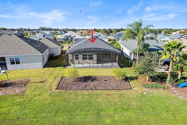 rear view of property with a lanai and a lawn