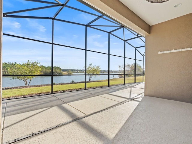 view of patio featuring glass enclosure and a water view