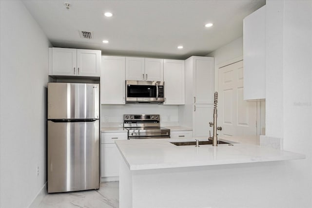 kitchen with kitchen peninsula, white cabinetry, sink, and appliances with stainless steel finishes