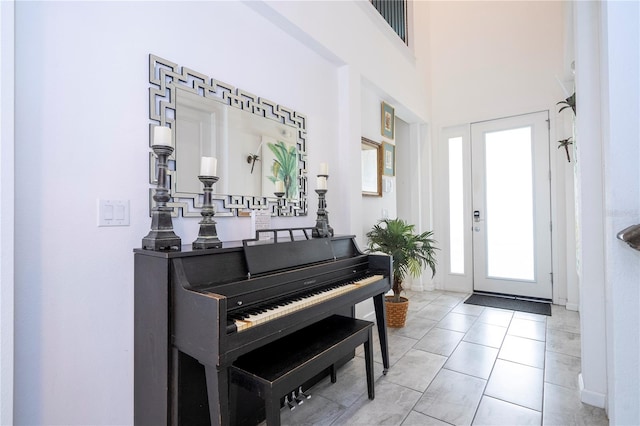 entryway with a healthy amount of sunlight, light tile patterned floors, and a high ceiling