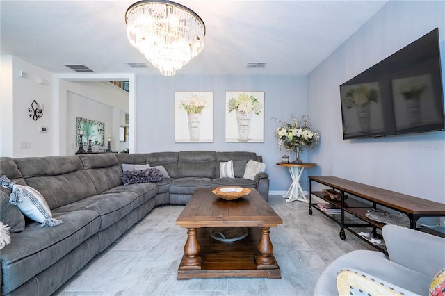 living room with a chandelier, a textured ceiling, and light wood-type flooring