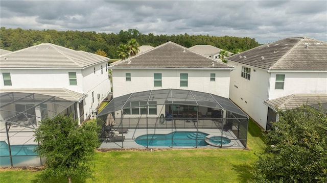 rear view of property with a patio area, a lawn, and a lanai