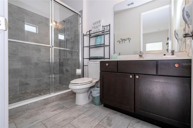 bathroom featuring vanity, toilet, and a shower with shower door