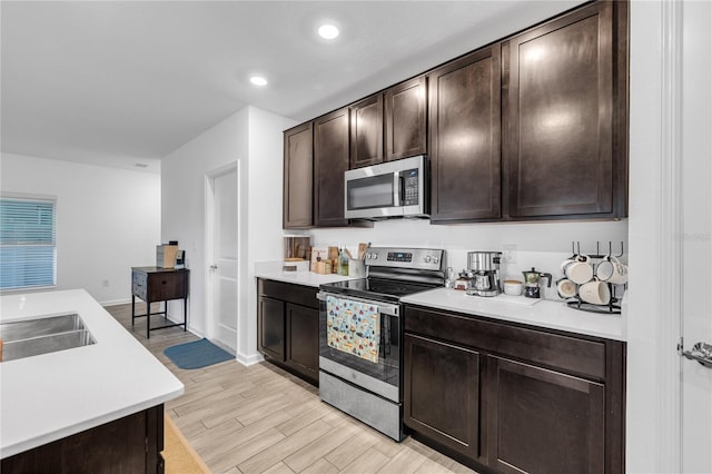 kitchen with sink, dark brown cabinetry, stainless steel appliances, and light hardwood / wood-style floors