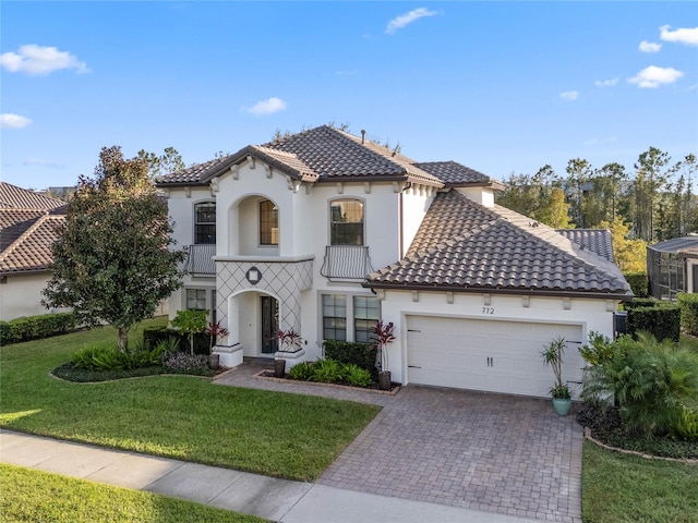 mediterranean / spanish home with a front lawn, a garage, and a balcony