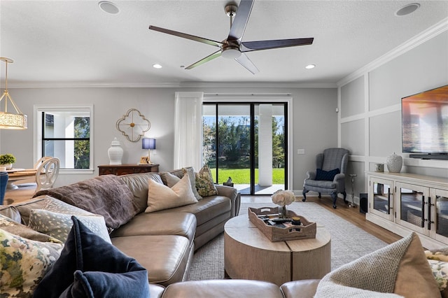 living room featuring a textured ceiling, ceiling fan, recessed lighting, wood finished floors, and crown molding