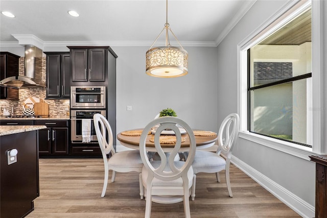 dining space with a healthy amount of sunlight, baseboards, crown molding, and light wood finished floors