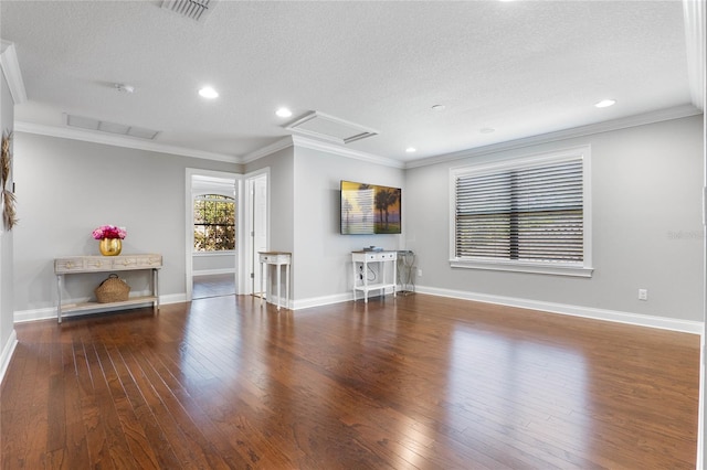 unfurnished living room with wood finished floors, attic access, and crown molding