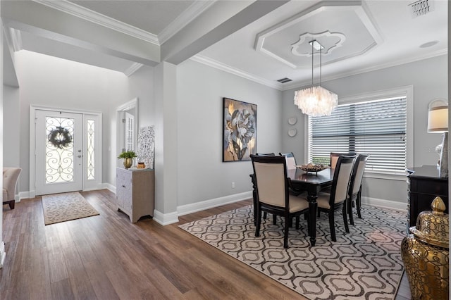 dining room with a notable chandelier, crown molding, visible vents, and wood finished floors