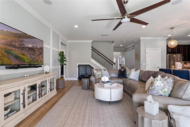 living area featuring stairs, wood finished floors, and crown molding