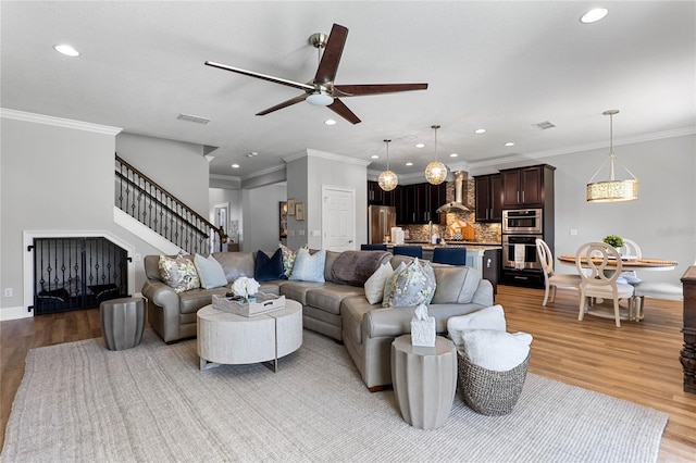 living area featuring recessed lighting, visible vents, light wood-style flooring, and stairs