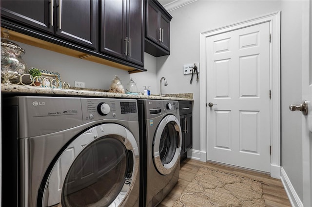 clothes washing area with cabinet space, light wood-style flooring, baseboards, and independent washer and dryer