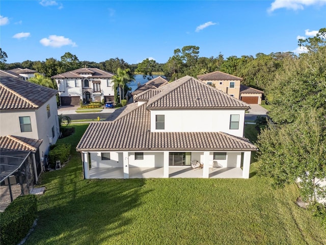 back of property with a tile roof, a residential view, a yard, a patio area, and stucco siding