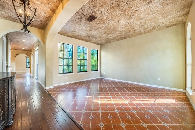 empty room with an inviting chandelier and dark hardwood / wood-style floors