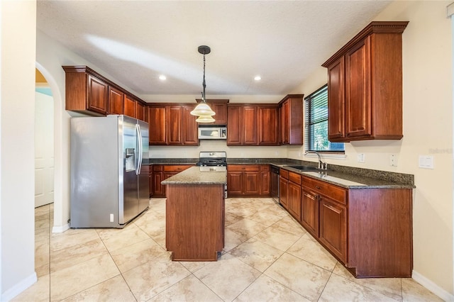 kitchen featuring appliances with stainless steel finishes, a textured ceiling, a center island, sink, and decorative light fixtures