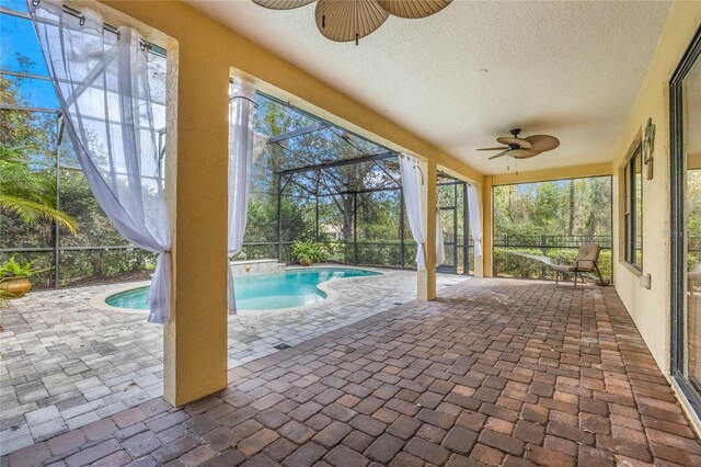 view of pool with a patio area, glass enclosure, and ceiling fan