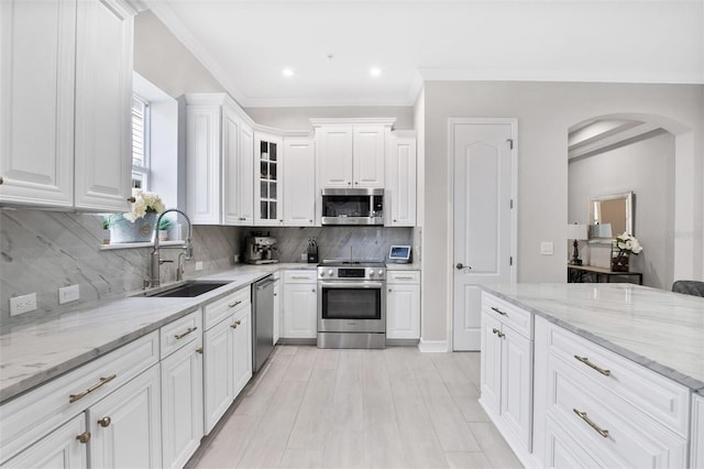 kitchen with white cabinetry, backsplash, stainless steel appliances, and sink