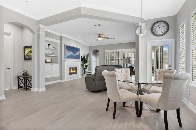 dining area featuring ceiling fan, light hardwood / wood-style floors, ornamental molding, and built in shelves