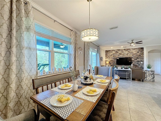 tiled dining area featuring ceiling fan and crown molding