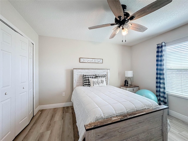 bedroom with ceiling fan, a textured ceiling, light hardwood / wood-style flooring, and a closet