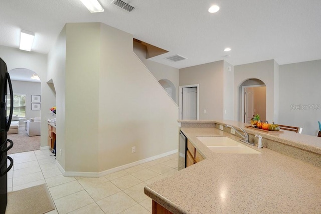 kitchen featuring stainless steel dishwasher, sink, and light tile patterned floors