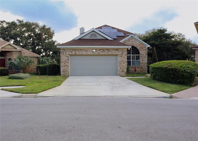 view of front of house featuring solar panels, a front lawn, and a garage