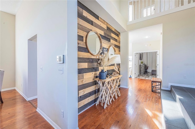 corridor with a towering ceiling and hardwood / wood-style floors