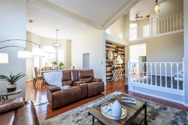 living room featuring dark wood-type flooring, a towering ceiling, and ceiling fan