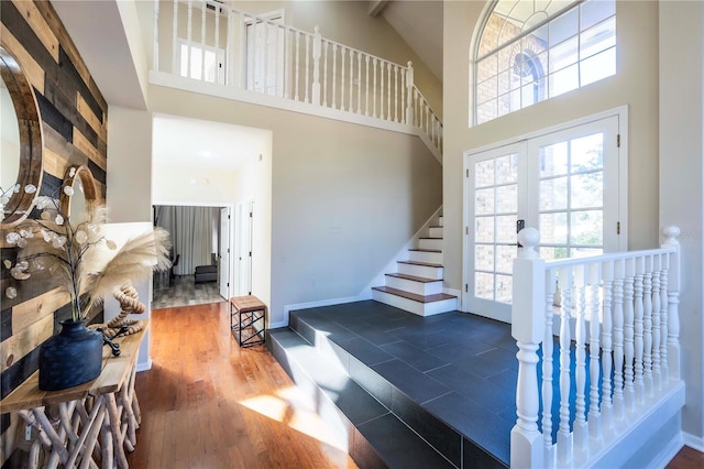 staircase featuring a towering ceiling, beam ceiling, and french doors