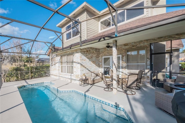 view of pool with ceiling fan, glass enclosure, and a patio