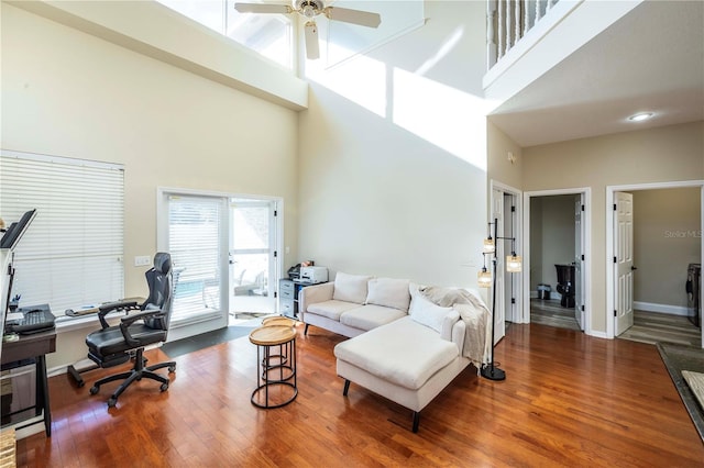 living room featuring a towering ceiling, ceiling fan, and hardwood / wood-style flooring