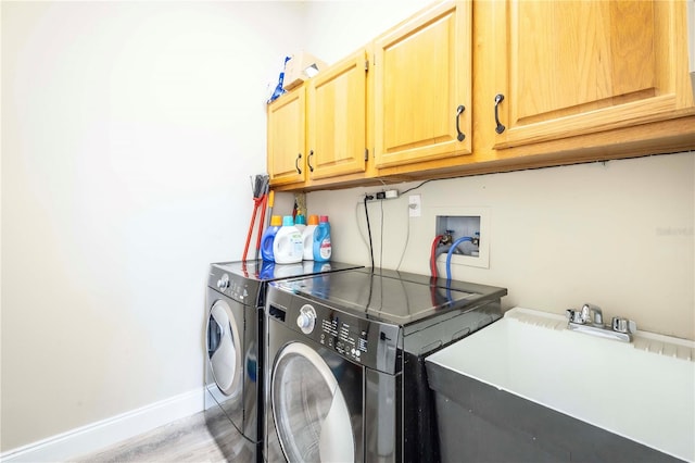 clothes washing area featuring separate washer and dryer, sink, and cabinets