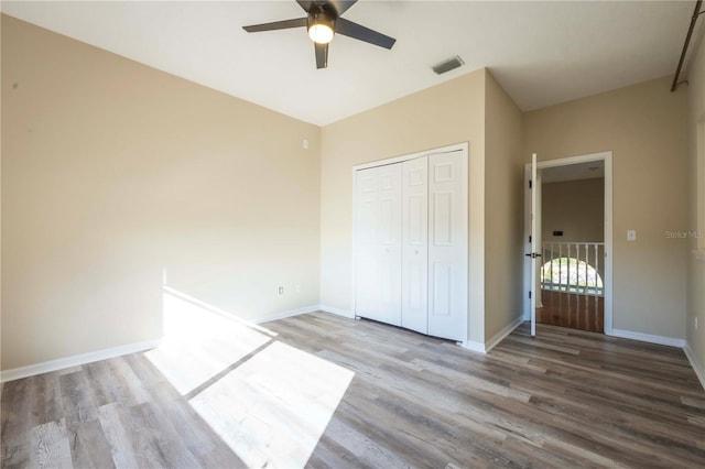 unfurnished bedroom featuring ceiling fan, hardwood / wood-style floors, and a closet