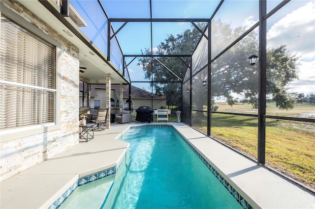 view of pool with area for grilling, a yard, a patio area, and glass enclosure