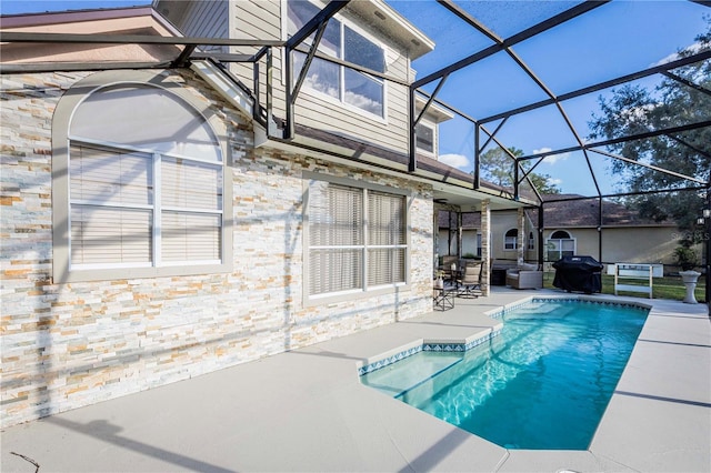 view of pool with grilling area, a patio, and glass enclosure