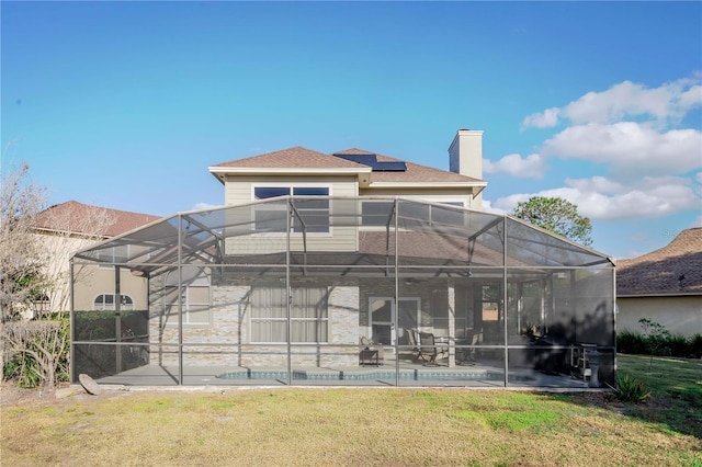 rear view of house with a pool, a yard, a patio, and solar panels