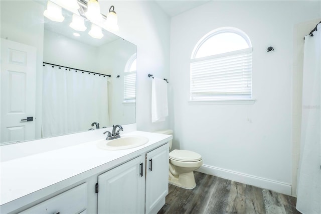 bathroom with vanity, plenty of natural light, wood-type flooring, and toilet