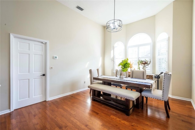 dining room with a high ceiling, wood-type flooring, and a notable chandelier