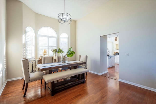 dining room with dark wood-type flooring, an inviting chandelier, and a high ceiling