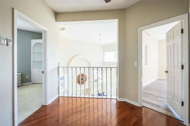 hallway featuring wood-type flooring and built in features