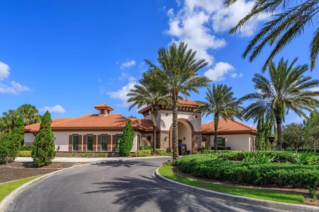 5295 Wildwood Way, Davenport, FL 33837 - mediterranean / spanish-style home featuring stucco siding, a tile roof, stone siding, and curved driveway