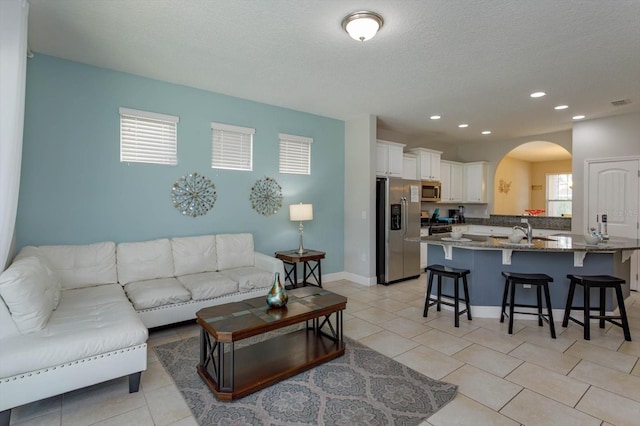5295 Wildwood Way, Davenport, FL 33837 - living room featuring arched walkways, light tile patterned floors, a textured ceiling, and recessed lighting