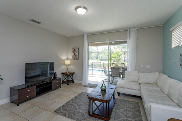 5295 Wildwood Way, Davenport, FL 33837 - living area featuring healthy amount of natural light, light tile patterned floors, a textured ceiling, and baseboards