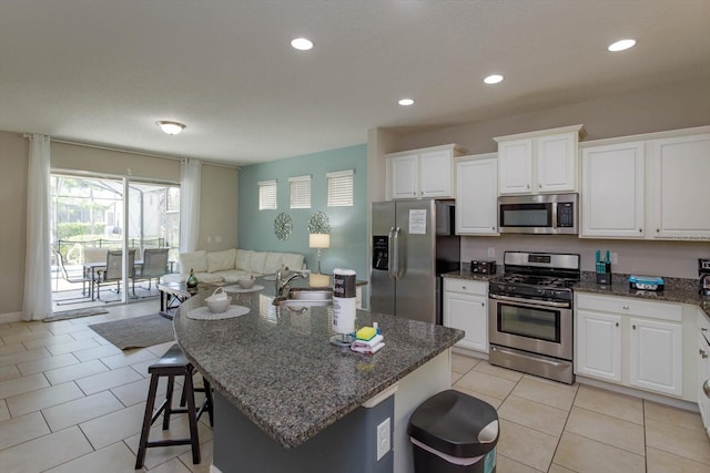 5295 Wildwood Way, Davenport, FL 33837 - kitchen featuring appliances with stainless steel finishes, dark stone counters, white cabinetry, a breakfast bar, and a sink