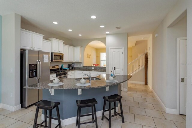 5295 Wildwood Way, Davenport, FL 33837 - kitchen with stainless steel appliances, a sink, arched walkways, recessed lighting, and a kitchen breakfast bar