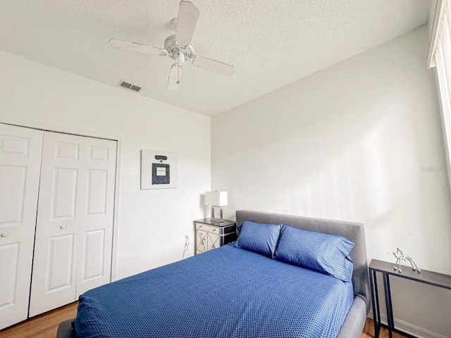 bedroom with ceiling fan, a closet, hardwood / wood-style floors, and a textured ceiling