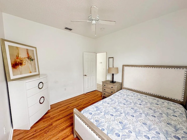 bedroom featuring ceiling fan, light hardwood / wood-style flooring, and a textured ceiling