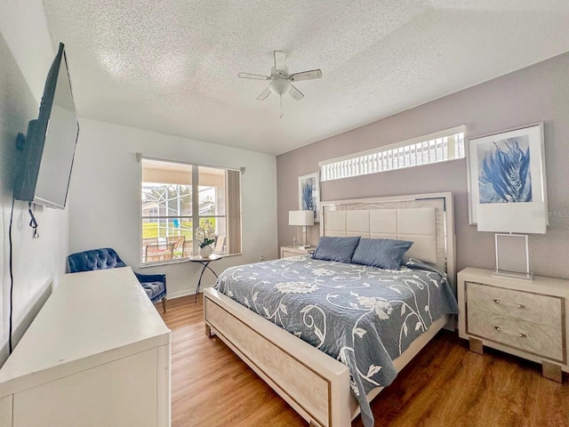 bedroom with ceiling fan, wood-type flooring, and a textured ceiling