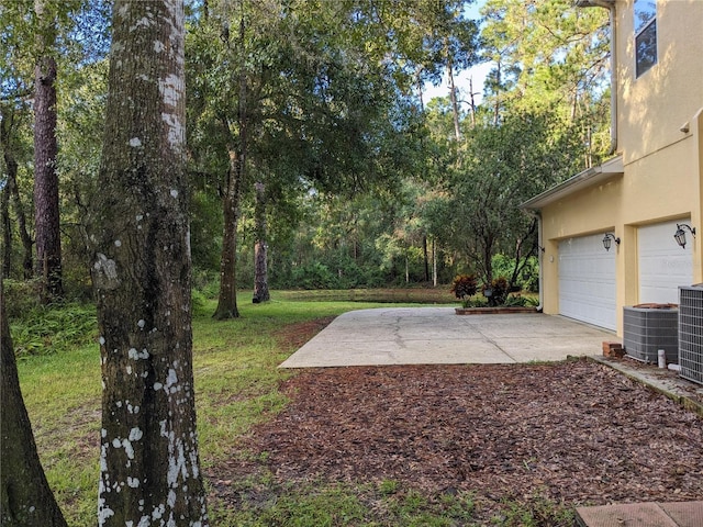 view of yard with a garage and central air condition unit