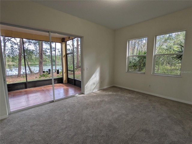 carpeted spare room with a water view, baseboards, and tile patterned floors